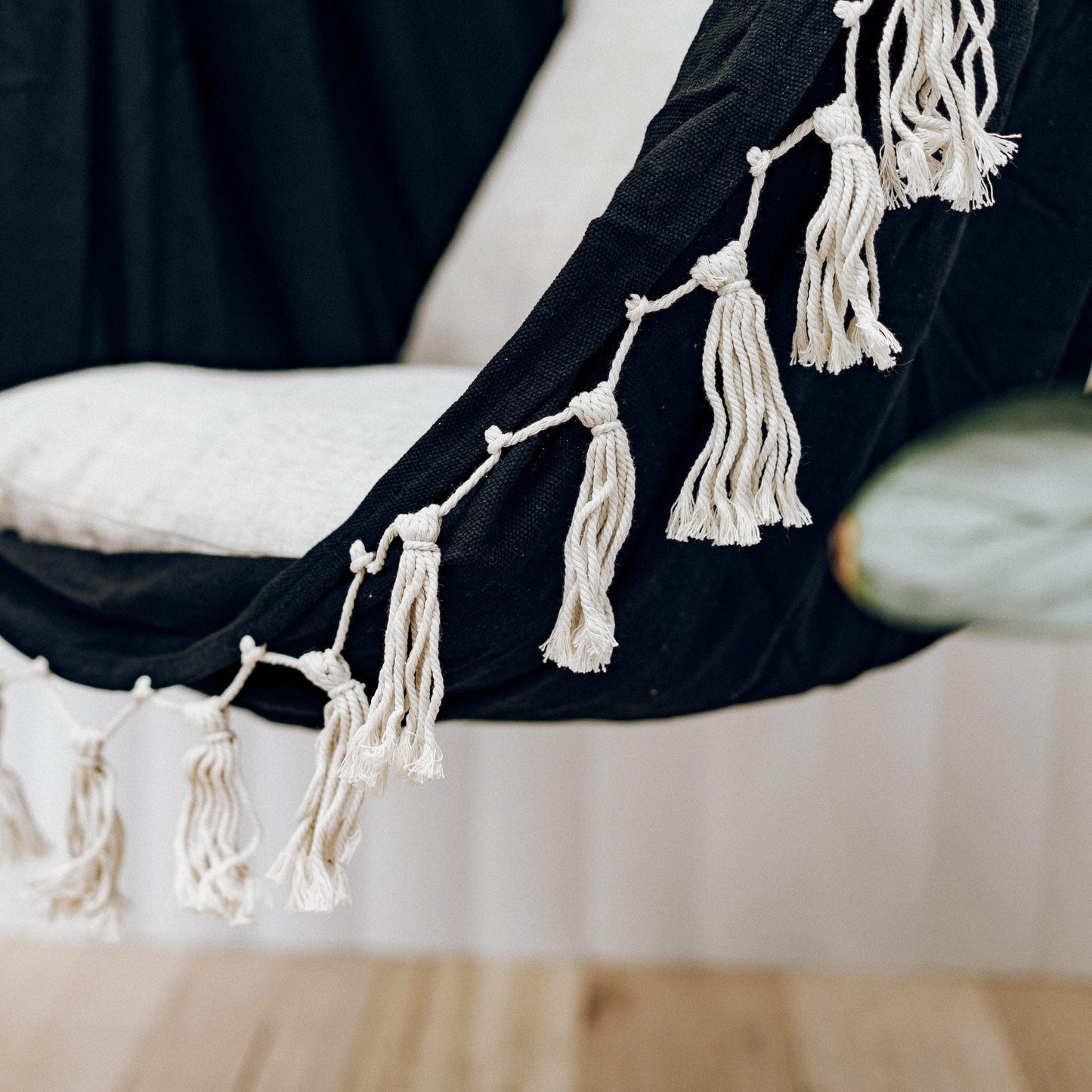Close-up of black hammock chair with cream macrame tassel fringe and rope ties