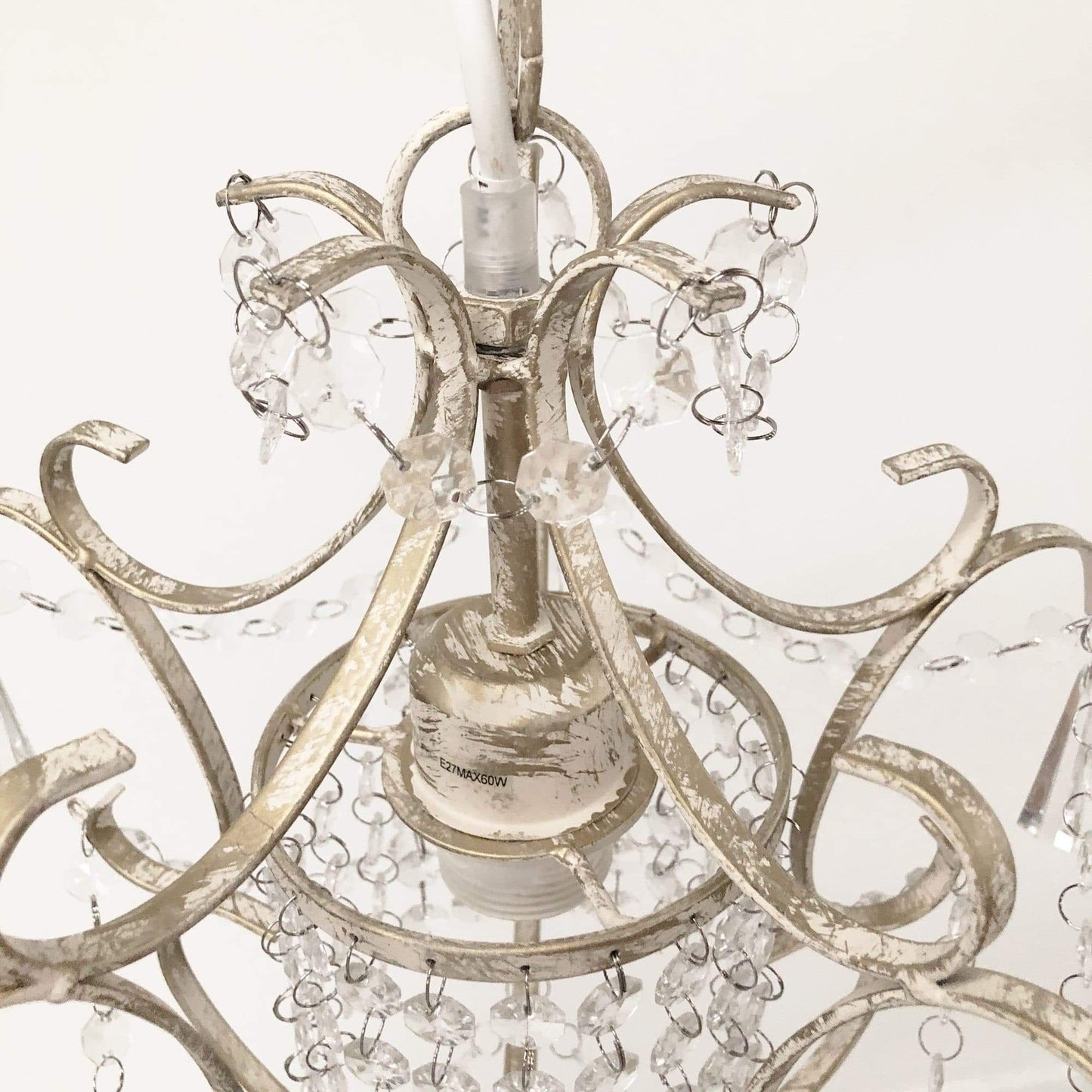 Close-up of clear crystal chandelier top with ornate metal scroll arms
