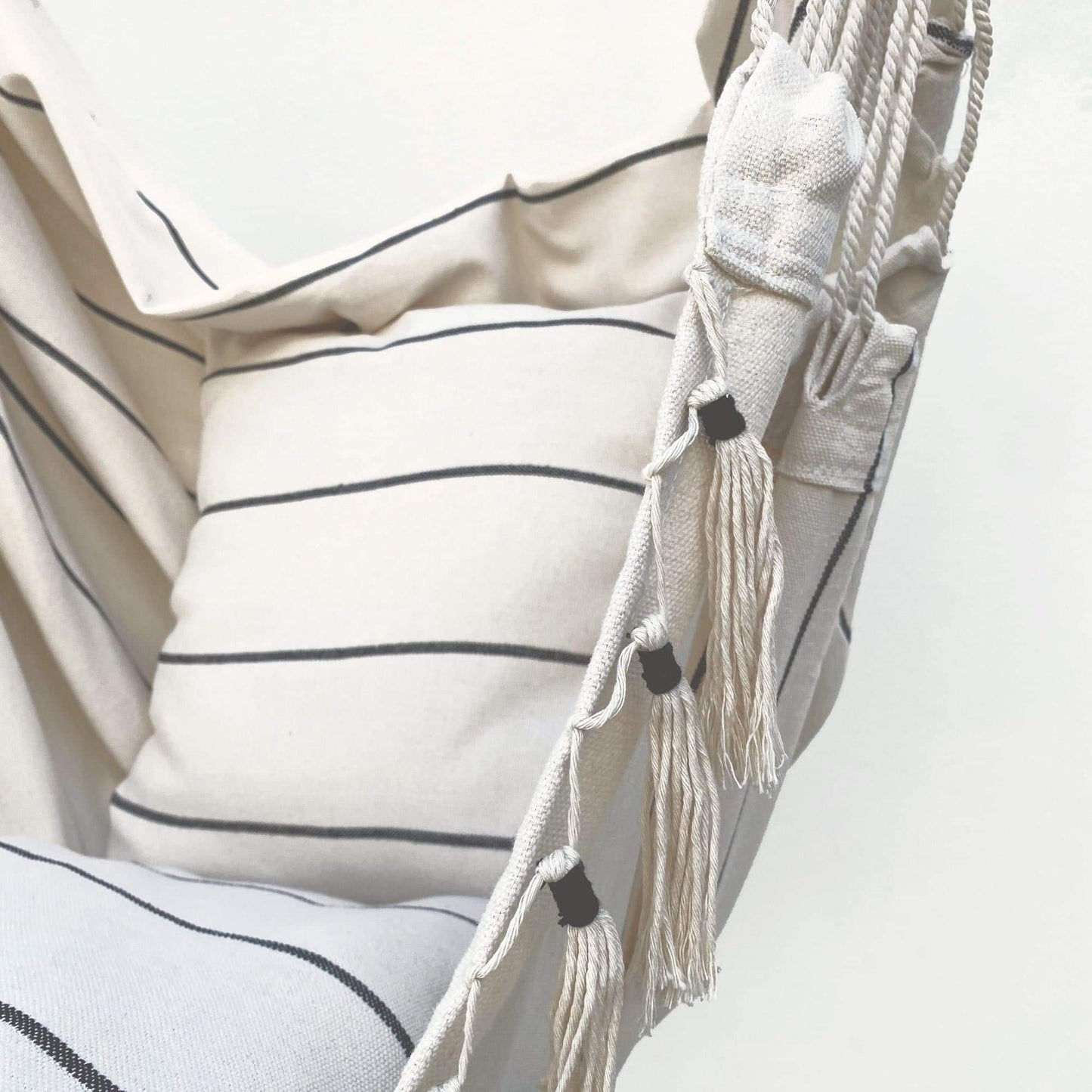 Cream striped hammock cushion with braided cord and fringe tassels, close-up