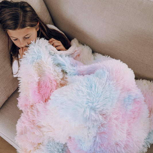 Pastel tie-dye shaggy fur throw blanket draped on a couch