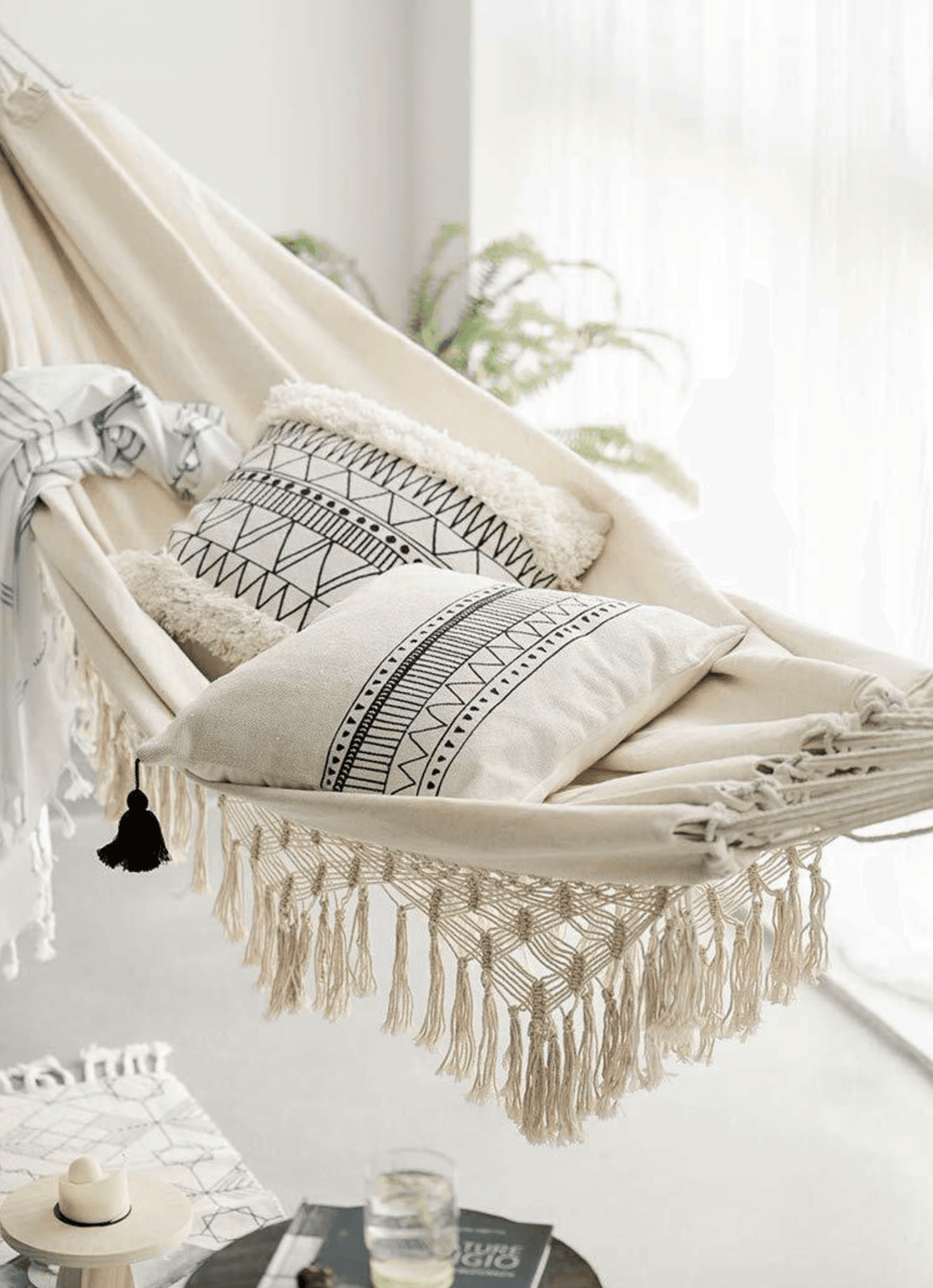 Cream hammock with long tassel fringe and patterned pillow resting in it