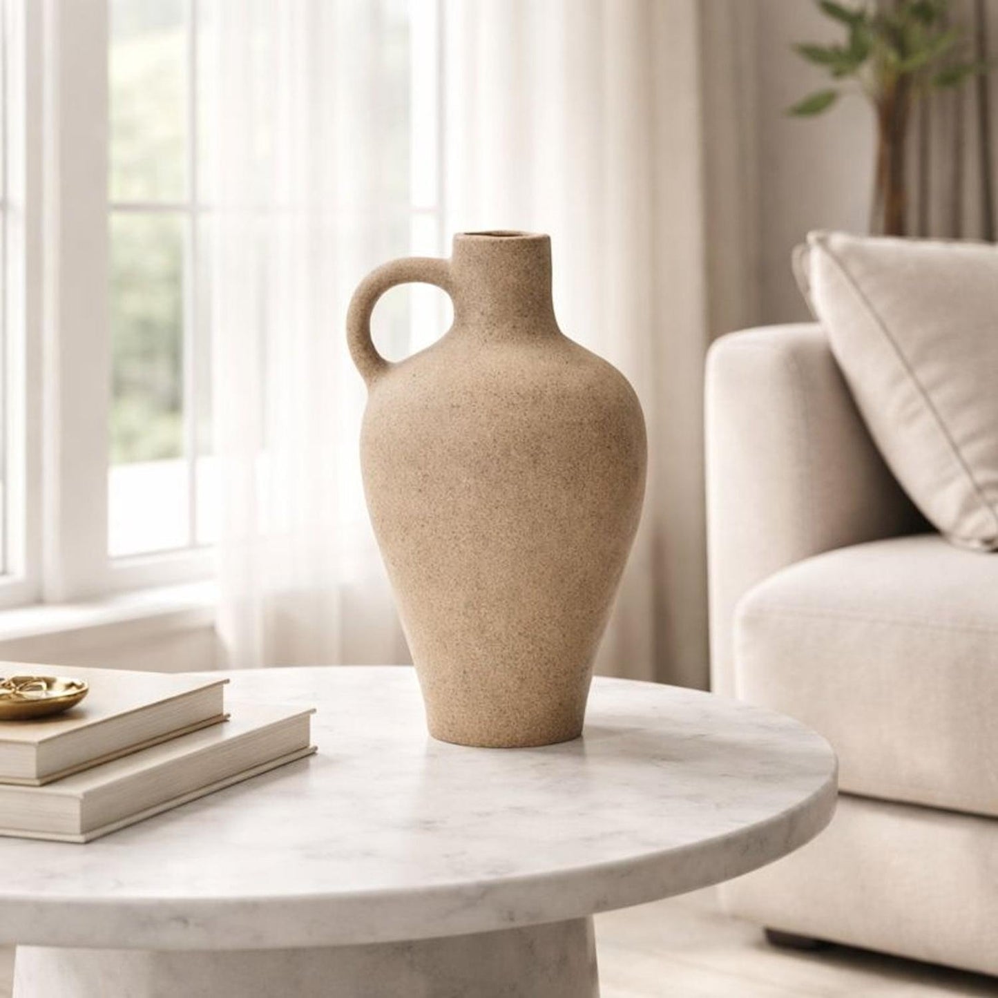 Beige speckled ceramic vase with round side handle on marble table