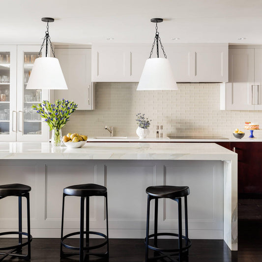 Pair of white fabric pendant lights with black chains over a kitchen island.