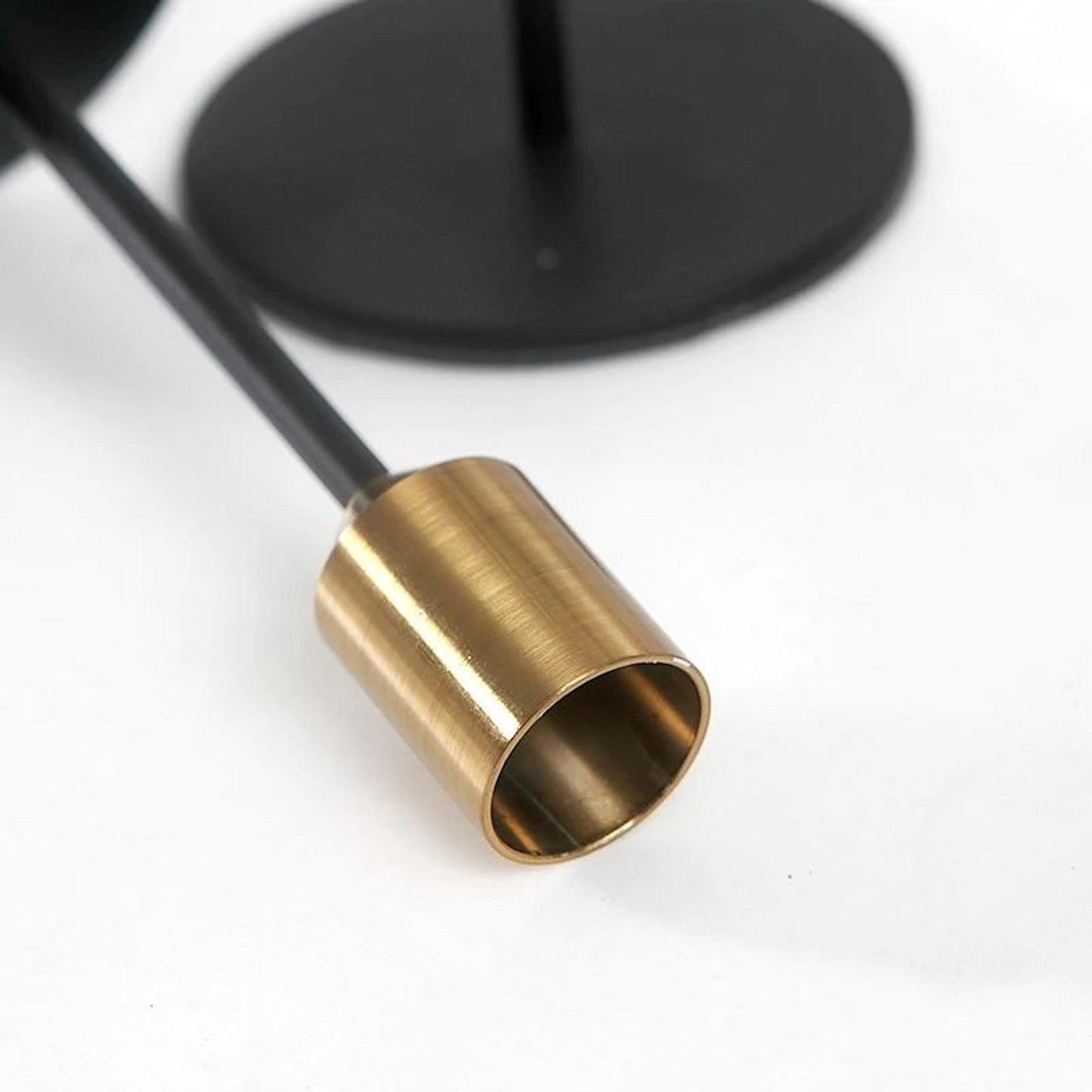 Close-up of brass candle cup on black candlestick stand