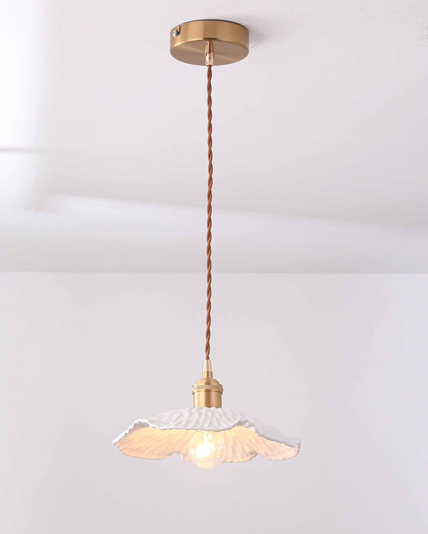 Pendant light with glowing white textured ceramic shade and brass ceiling mount