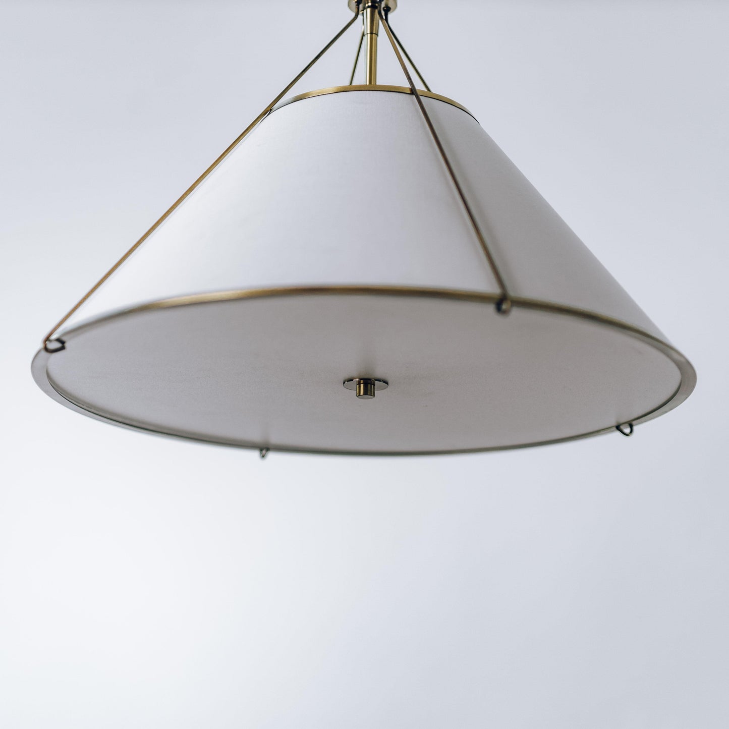 Brass pendant light with white fabric bell shade and central brass canopy