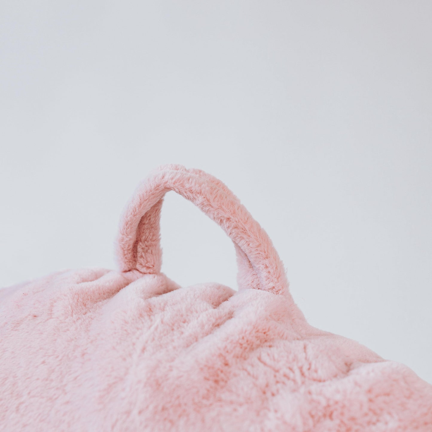Soft pink mini beanbag chair with stitched carry handle loop on top.