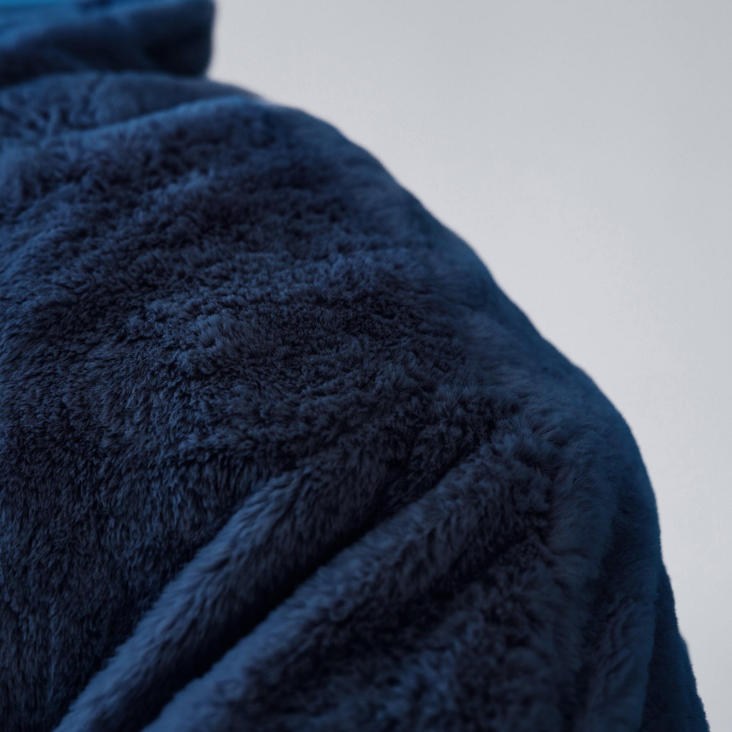 Navy blue plush beanbag chair fabric texture with curved stitched seam