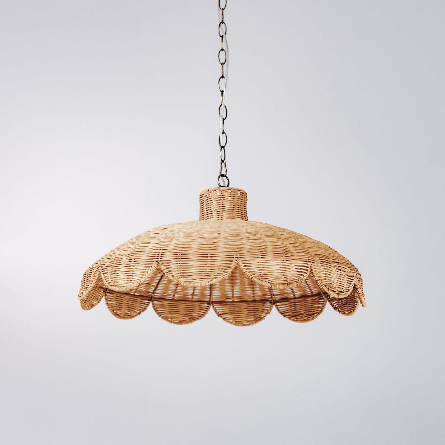 Natural rattan scallop pendant light with woven scalloped hem and hanging metal chain.