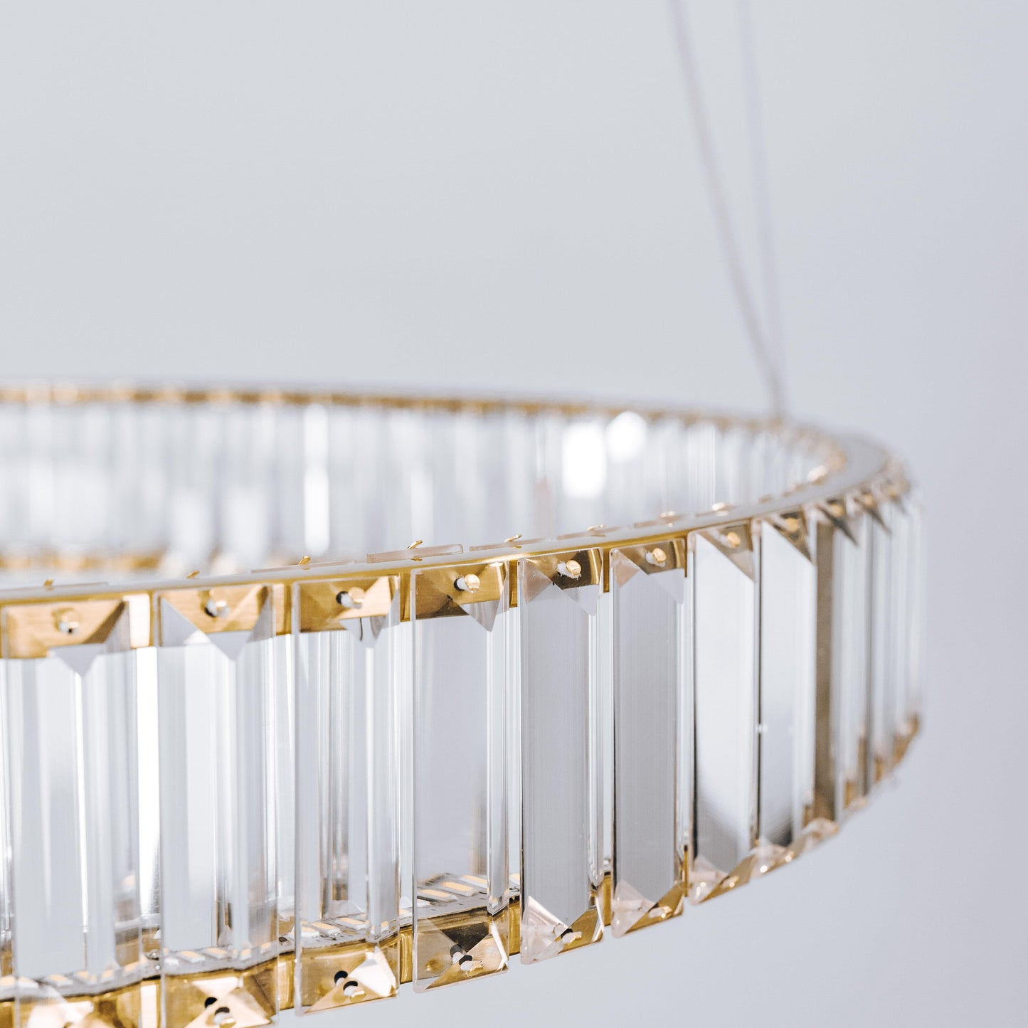 Close-up of round crystal LED chandelier with gold lattice and clear hanging prisms
