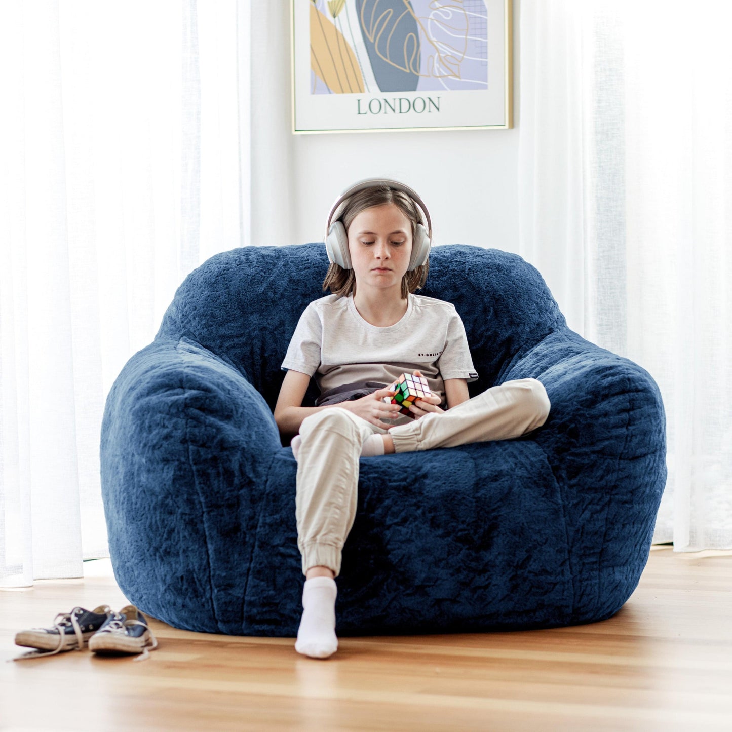 Navy blue plush lounge beanbag chair with wide arms and rounded seat.