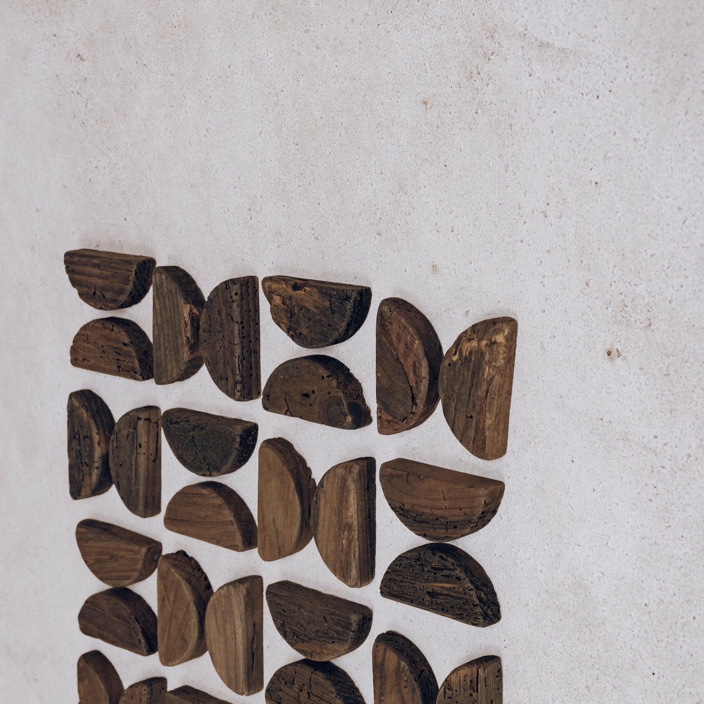 Wall art detail with scattered dark wood leaf-shaped pieces on off-white background
