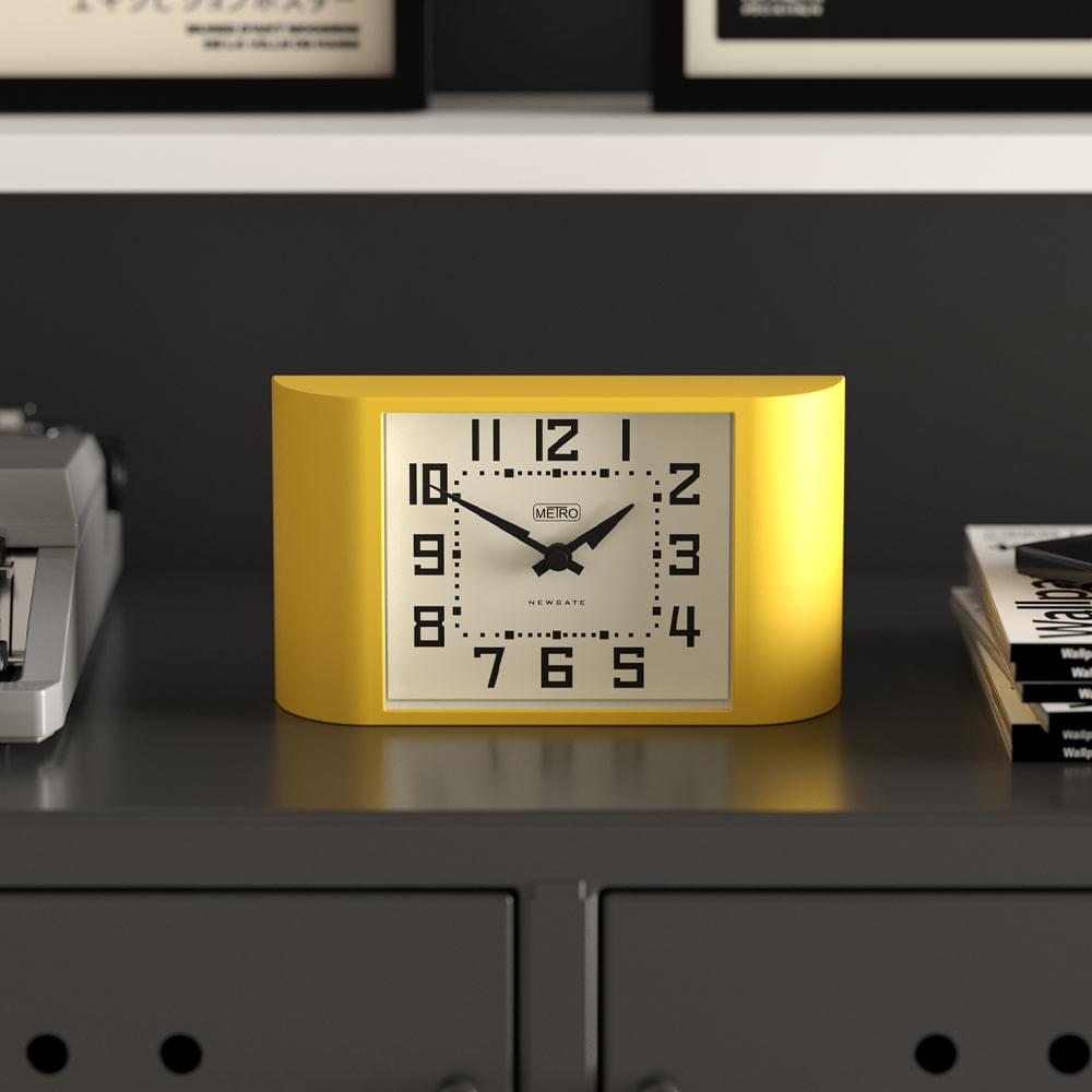 Yellow mantel clock with white face, black numerals, and black hands, front view