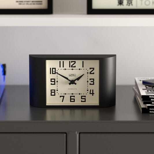 Black mantel clock on shelf with cream dial, black hands, and raised numerals