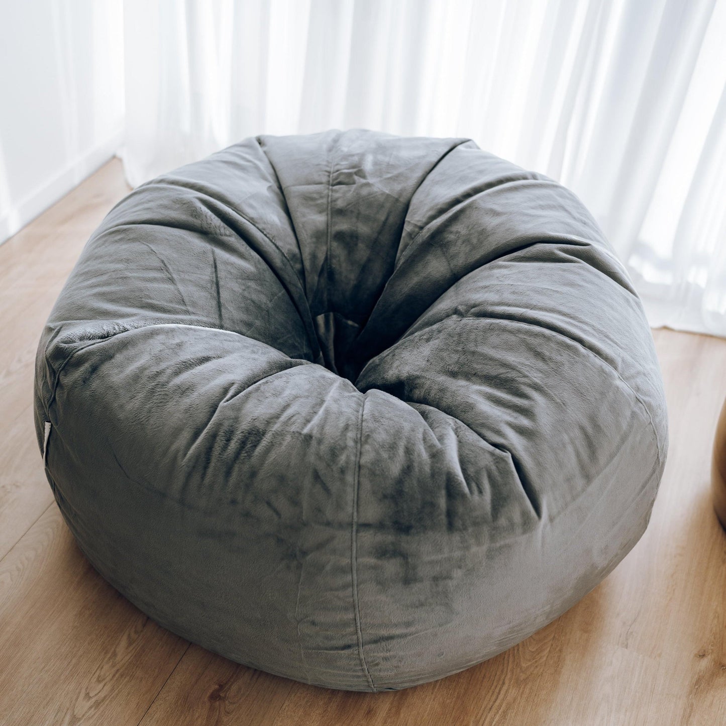 Charcoal round bean bag with stitched panels and deep, lounge-ready cushion