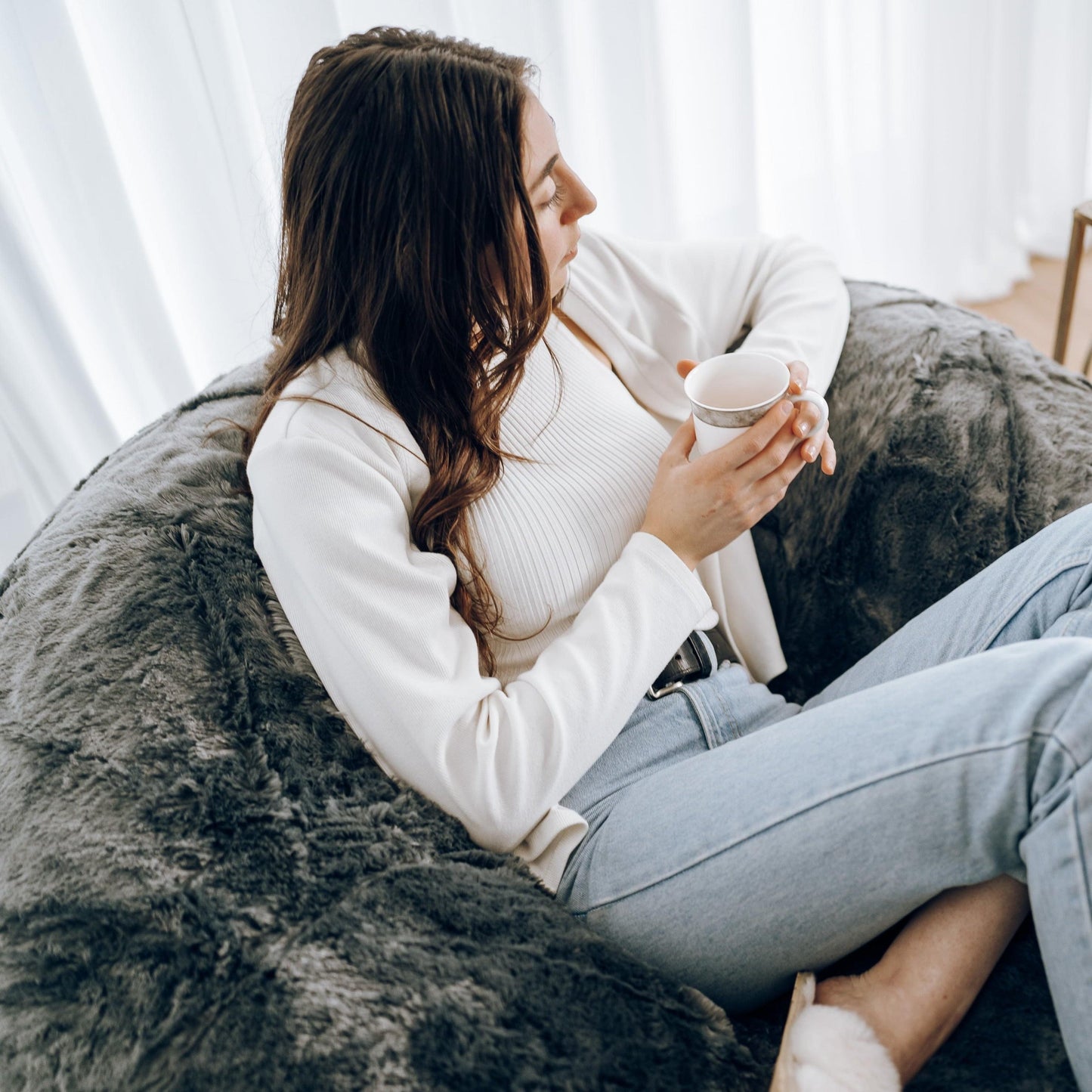 Charcoal plush fur bean bag with shaggy surface, person relaxing