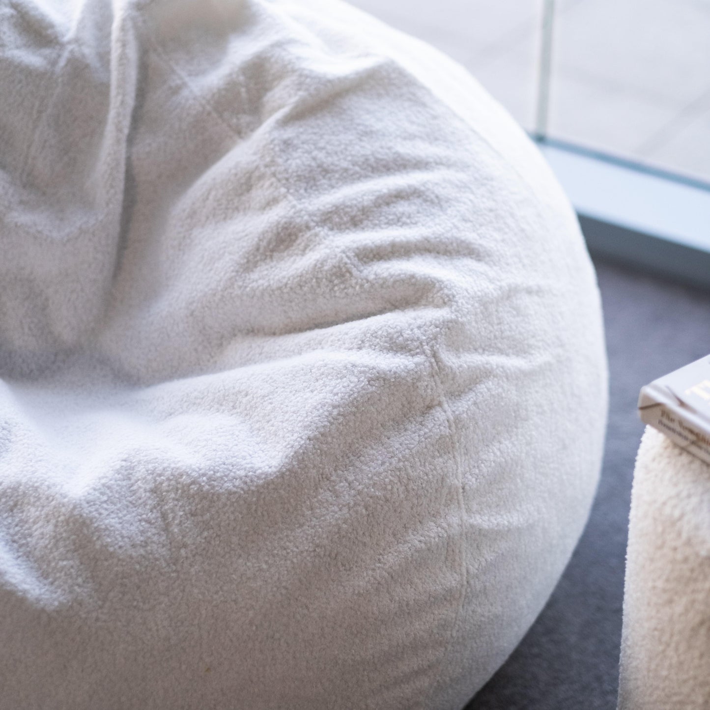 Close-up of white boucle bean bag fabric texture and gathered seam detail.