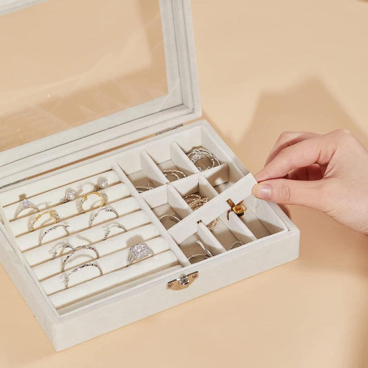 Jewelry box with glass lid open, divided slots, and a hand closing the lid