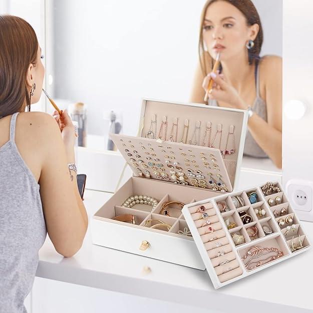 Open white jewelry box organizer on tabletop with compartments for necklaces and rings