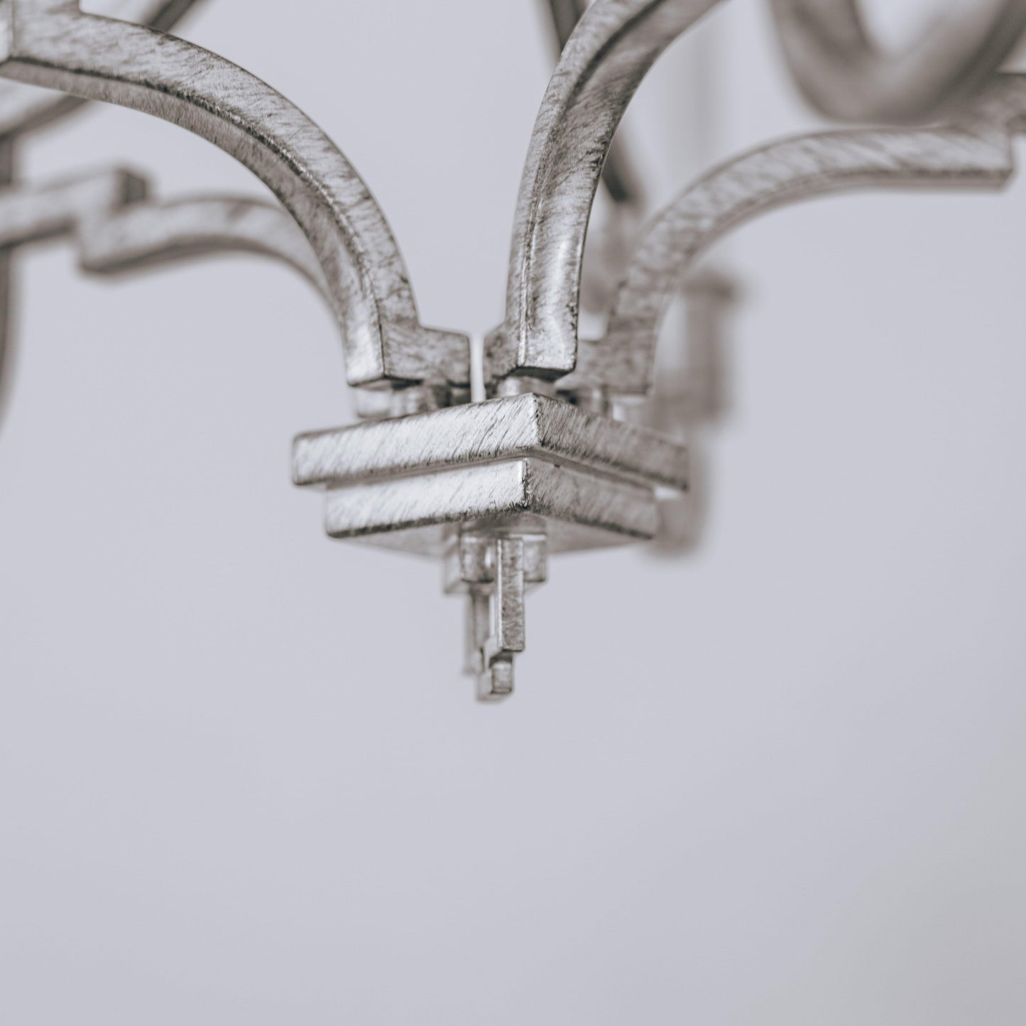 Brushed silver chandelier arm with crossbar mount and candle socket details