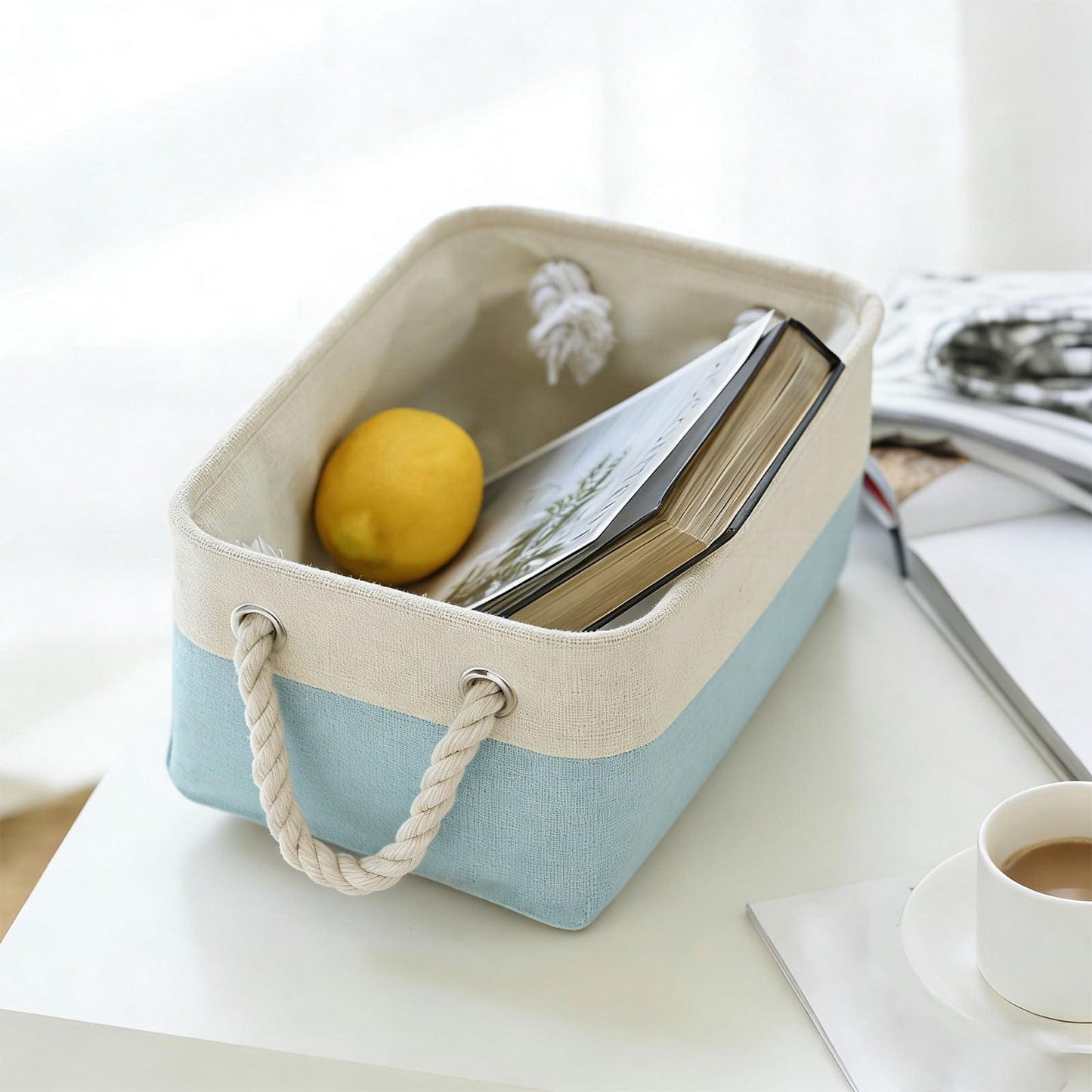 Light gray and light blue fabric storage box with rope handles, holding books