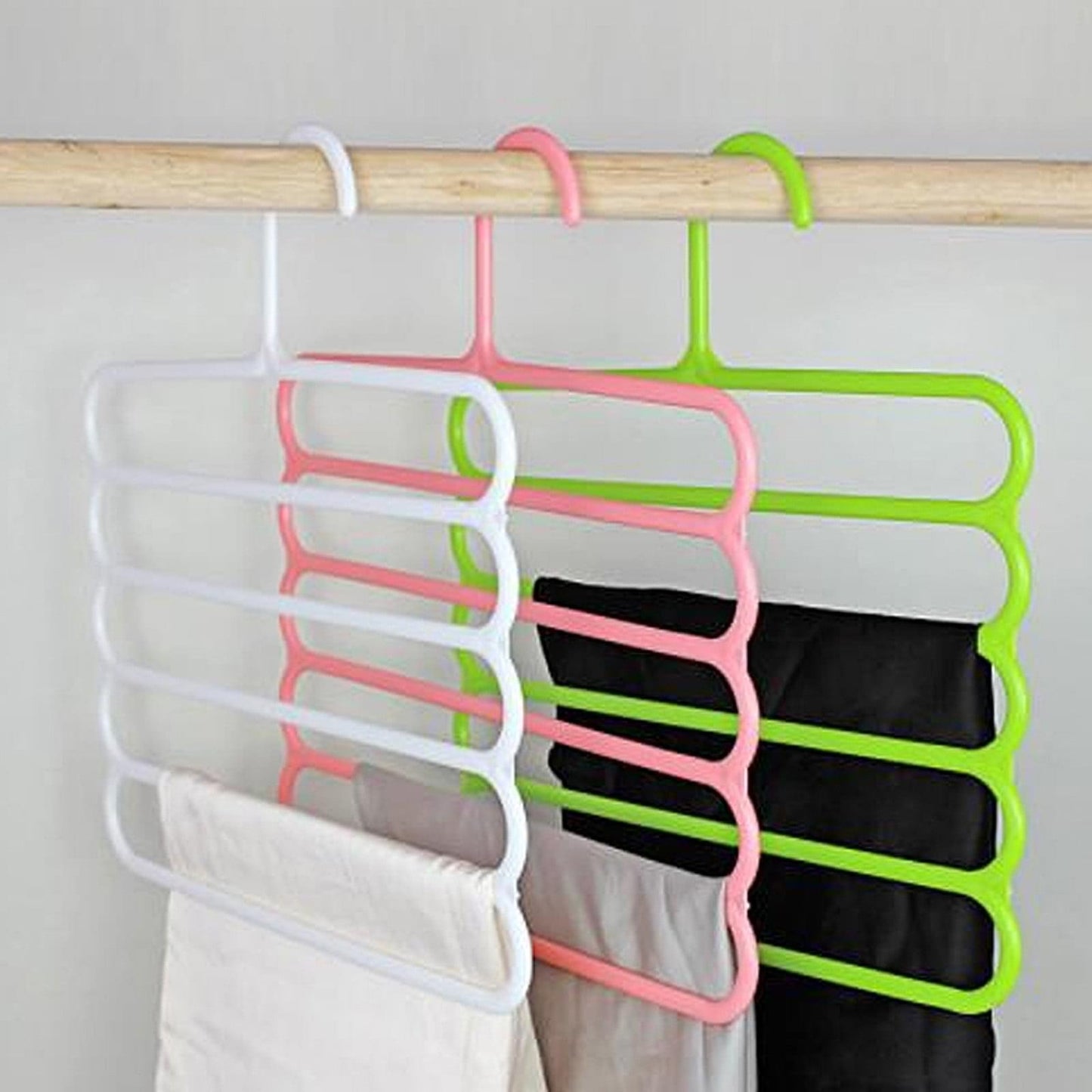 White, pink, green, and black tiered pants hangers with folded clothes