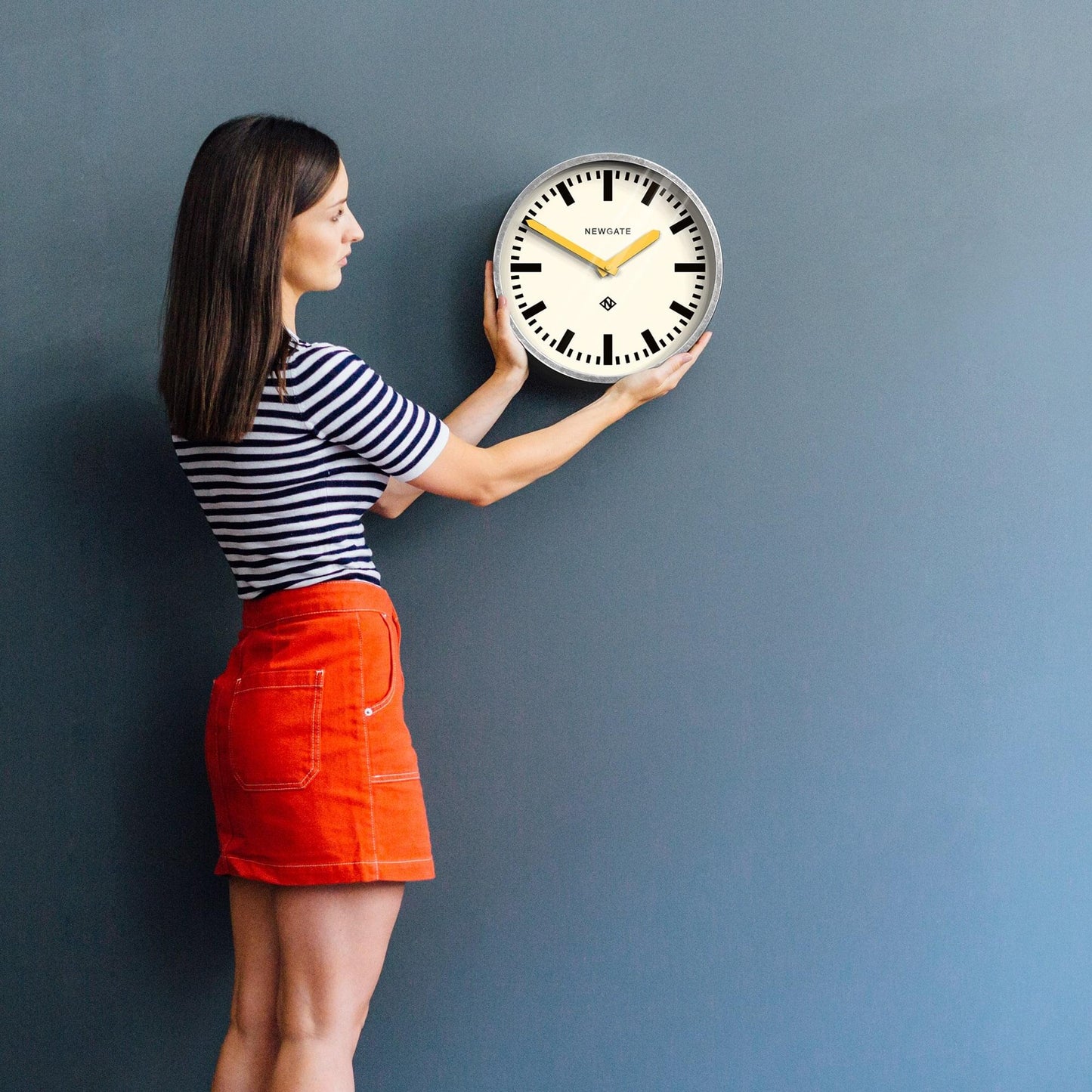 Wall clock with cream face, black markers, and yellow hands mounted on a wall