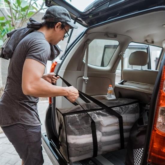 Large clear moving bag with black straps and handles in car trunk