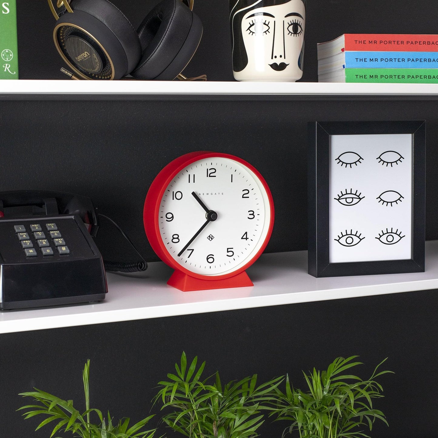 Red mantel clock on shelf with white dial and black hands