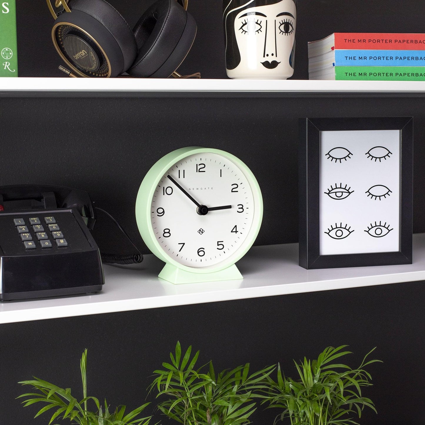 Neo mint round mantel clock on a shelf with black numerals and hands
