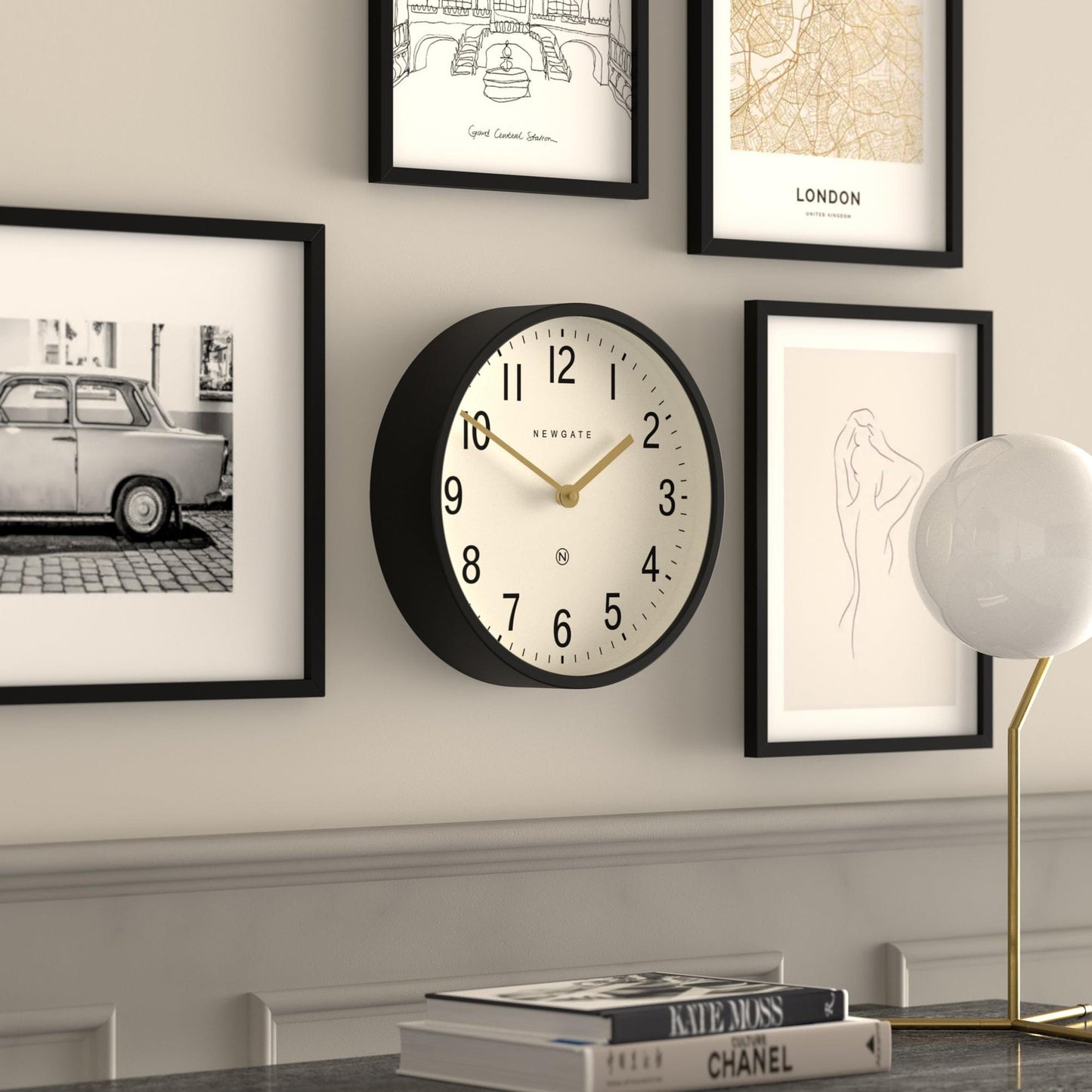 Black wall clock with cream face, gold hands, and Arabic numerals on the dial.
