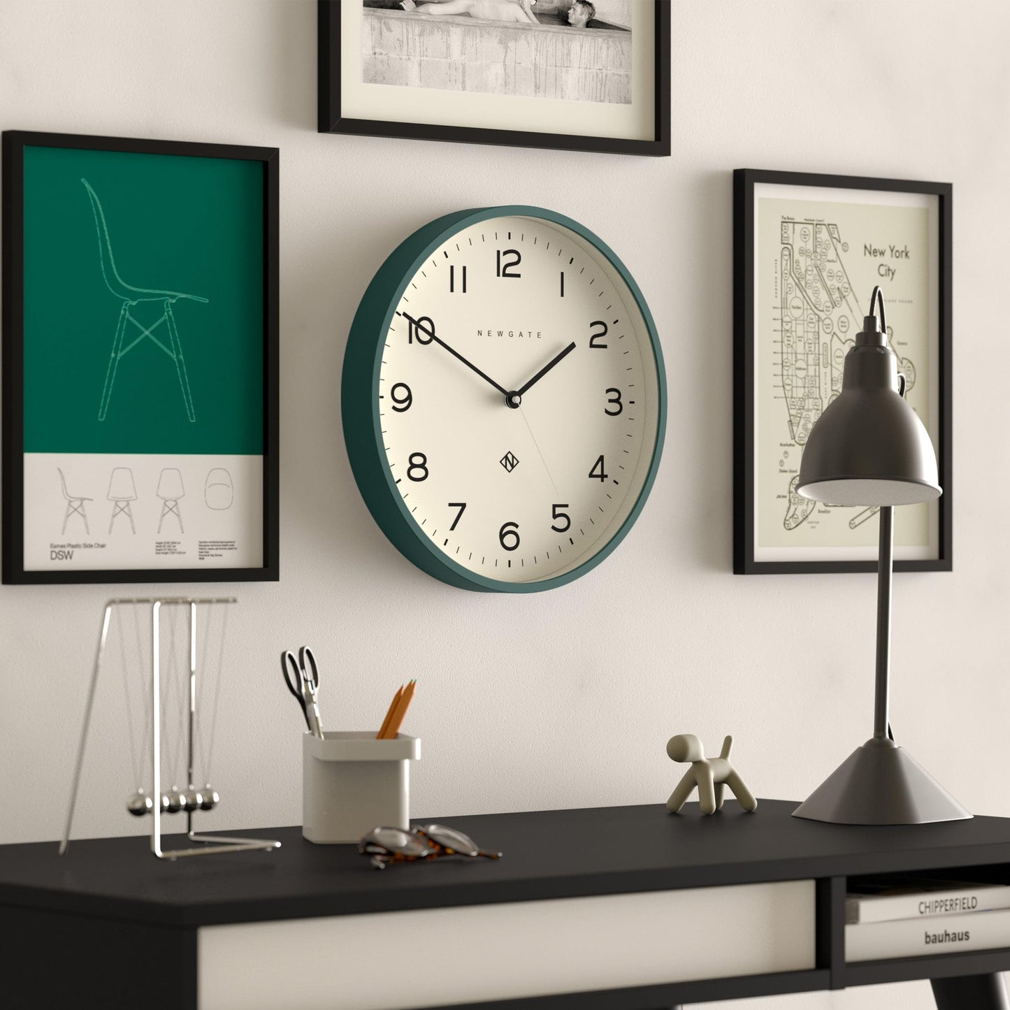 Green framed wall clock with white face, black hands, and Arabic numerals