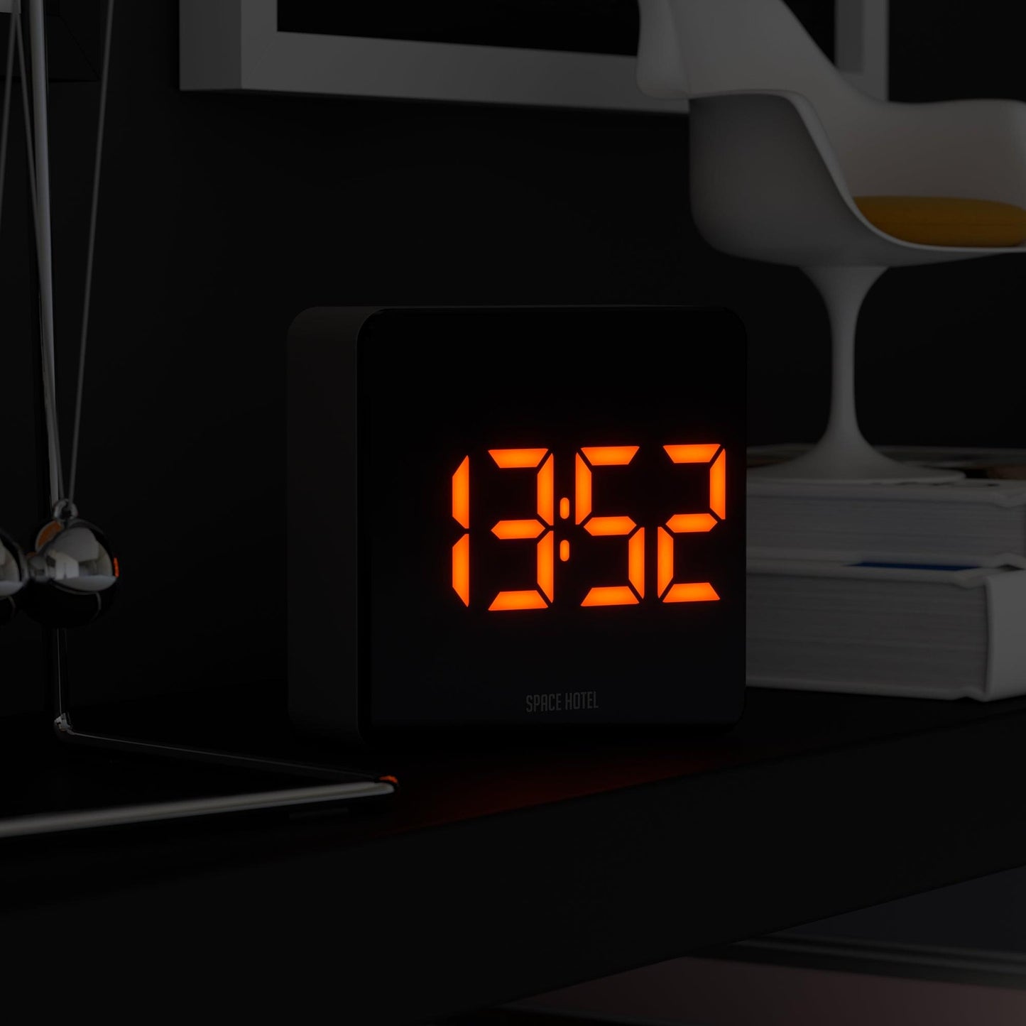 Black digital alarm clock with glowing orange LED digits and “SPACE HOTEL” below