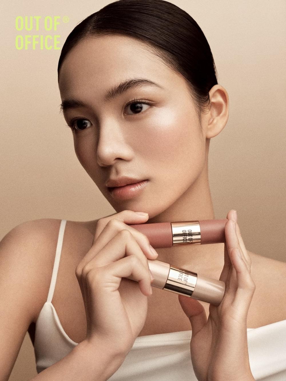 OUT OF OFFICE liquid blush tubes held to cheek with radiant nude-pink glow