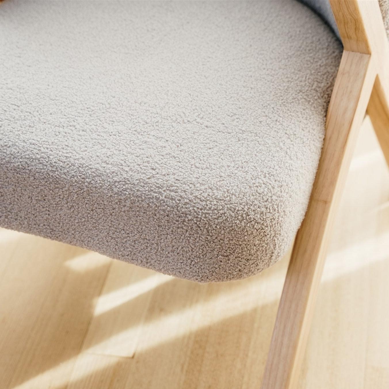 Soft grey boucle accent chair seat texture detail with light wood armrest