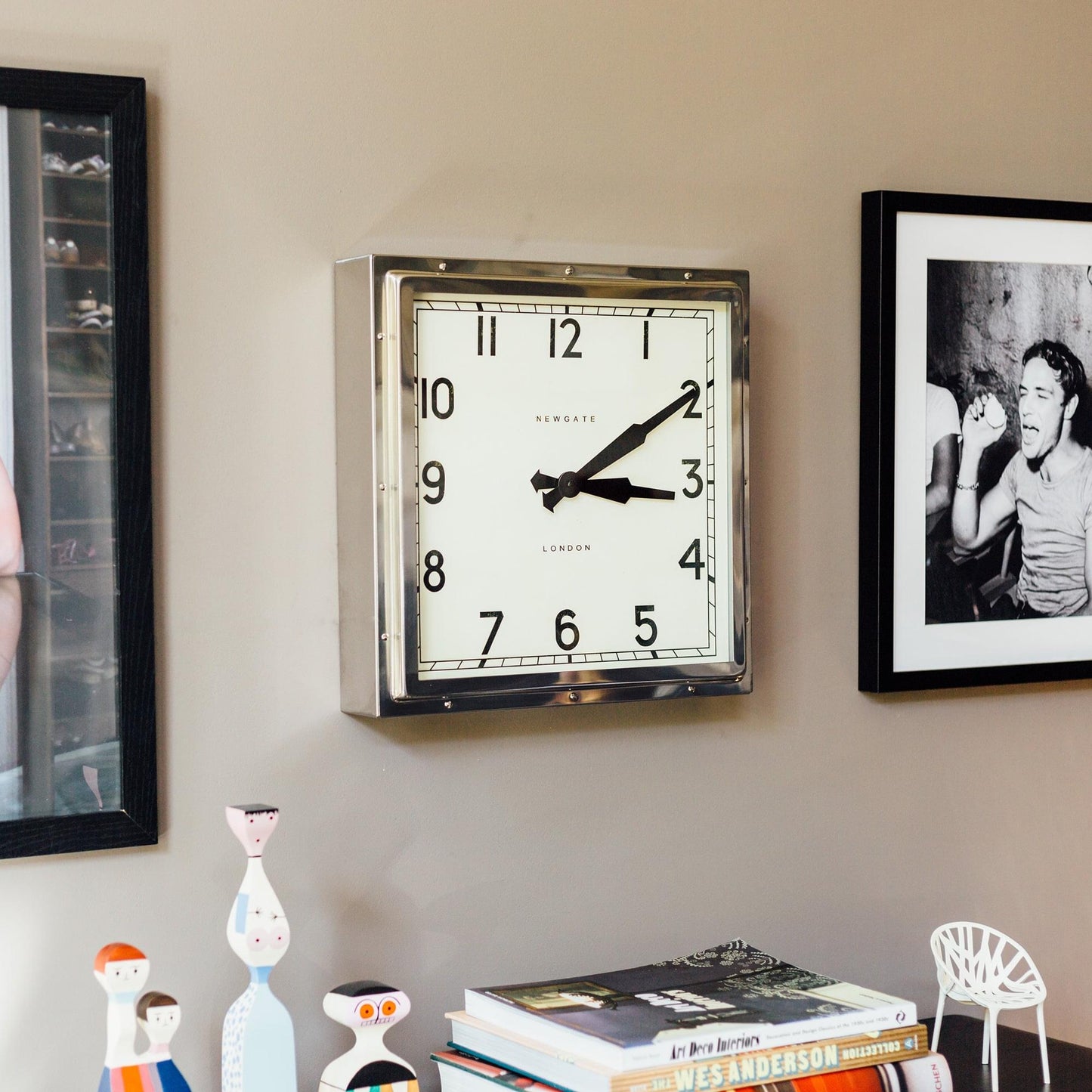 Wall-mounted chrome square clock with white dial and black hands