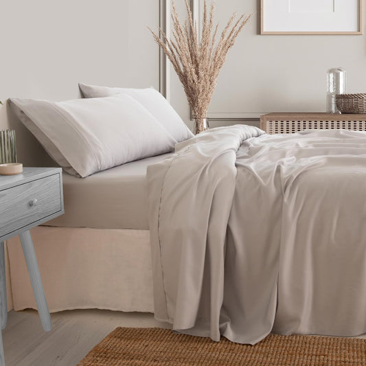 Light grey sheet set on king bed with pillowcases and draped bedspread