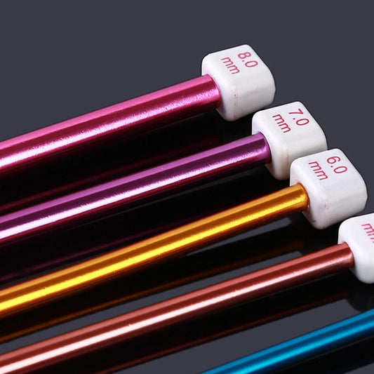 Close-up of long Tunisian crochet hooks with colored aluminum shafts and numbered white tips