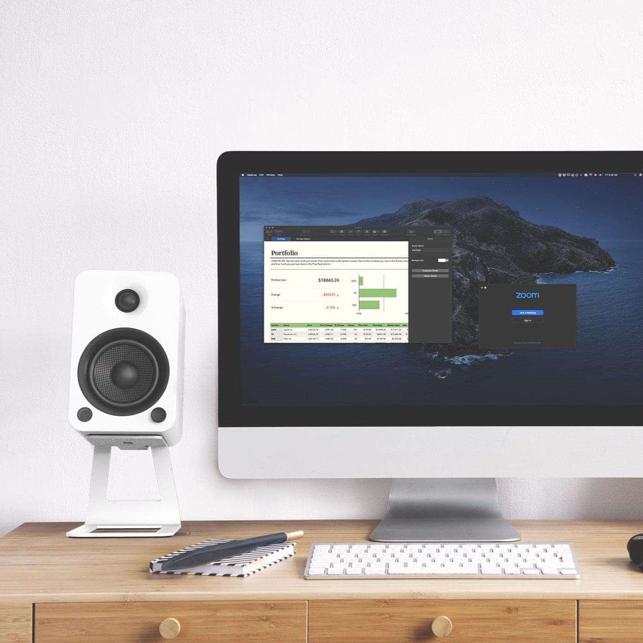 White desktop speaker stands holding a speaker on a desk