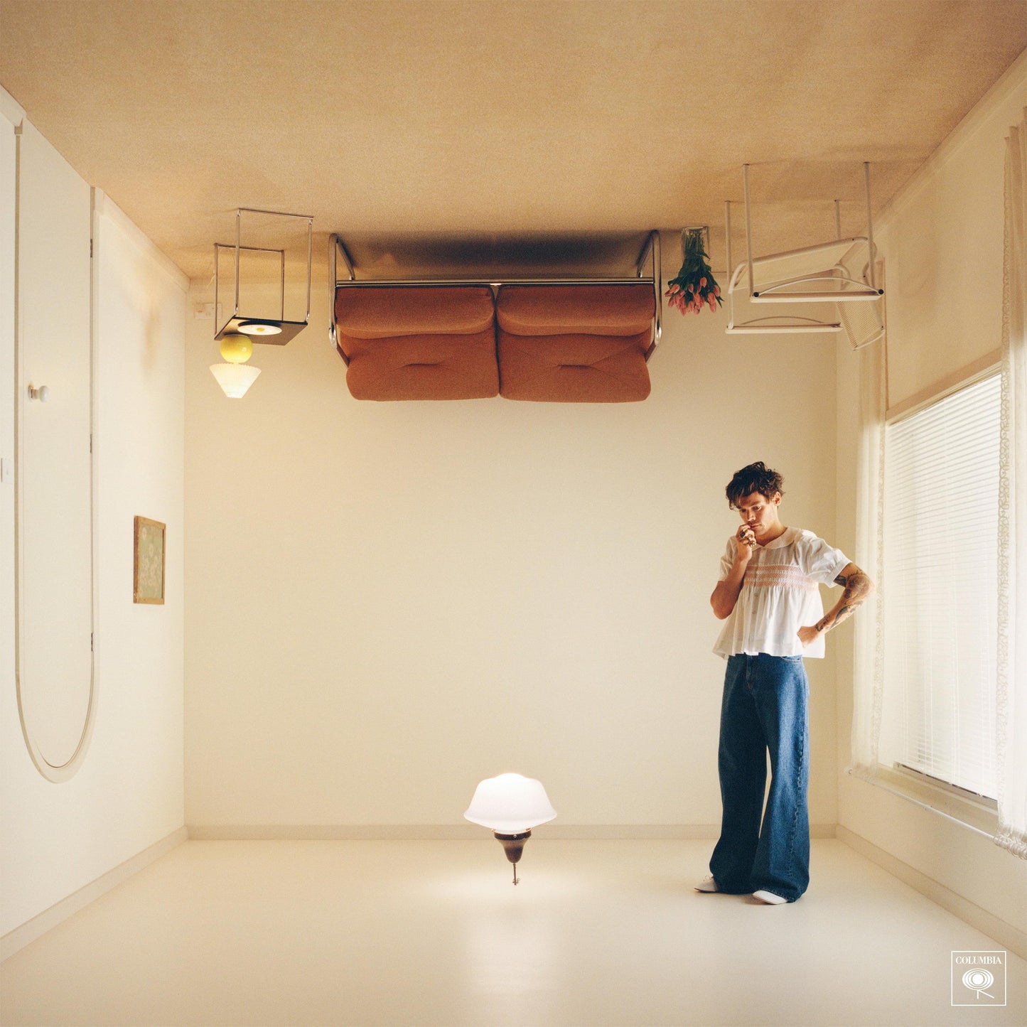 CD album; person standing indoors with hand near mouth, wearing a white top and jeans