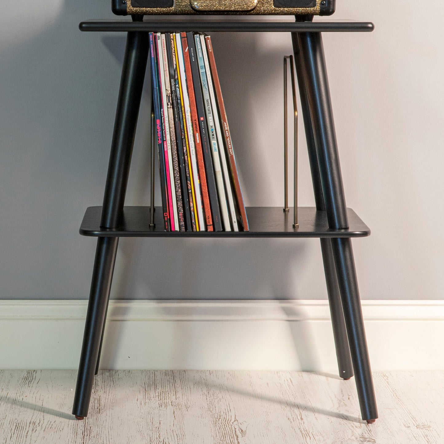 Black turntable stand shelf holding upright record collection and multiple spines
