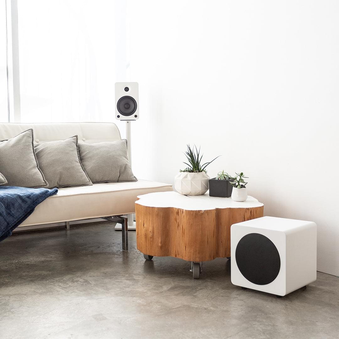 Matte white powered sealed subwoofer with black front grille and four feet