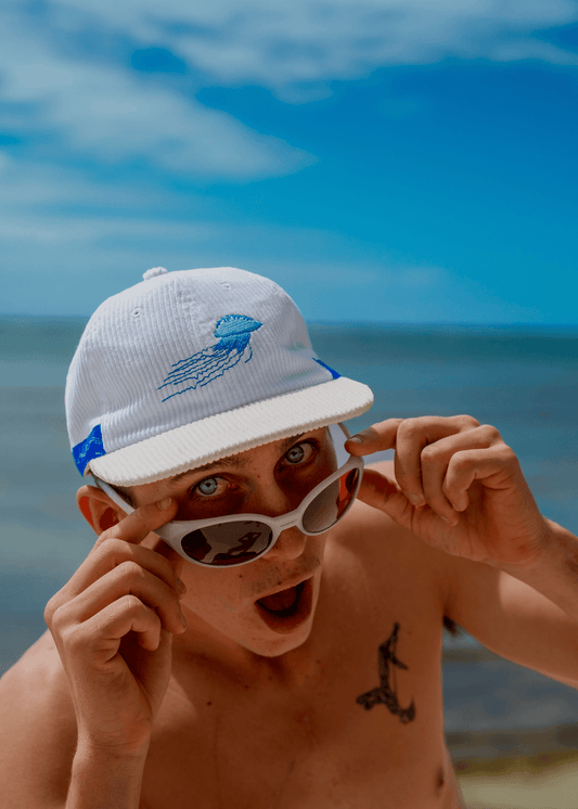 White baseball cap with blue jellyfish embroidery on front panel, curved brim.