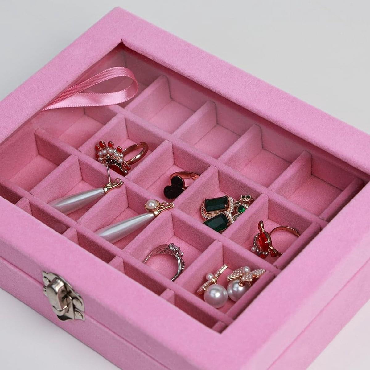 Velvet jewelry box with glass lid, pink, 24 compartments holding rings and earrings.