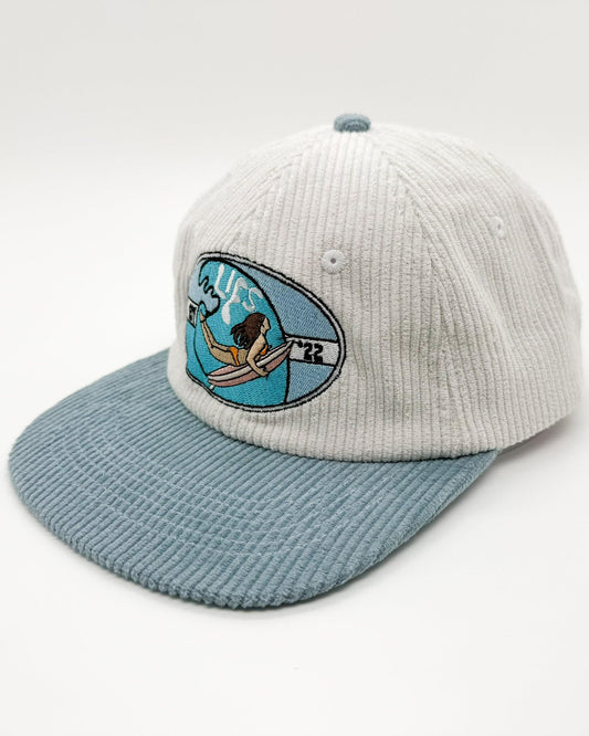 Two-tone knit baseball cap with light blue brim and front ocean surfer patch