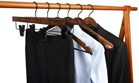Wooden pant hangers with black clips holding dark and light pants on a bar.