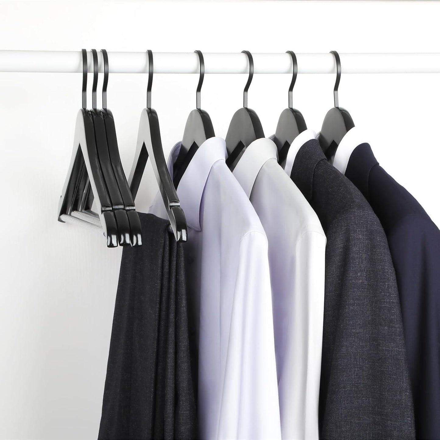 Group of black wooden hangers holding shirts, sleeves and collars facing forward