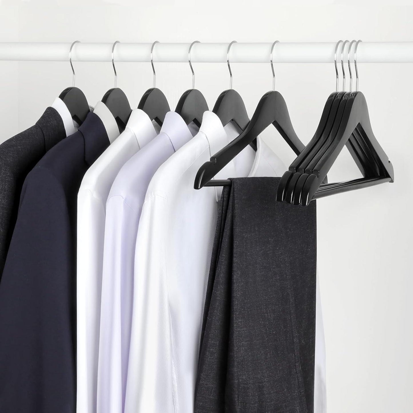 Set of black, white, and navy wooden coat hangers on a rack