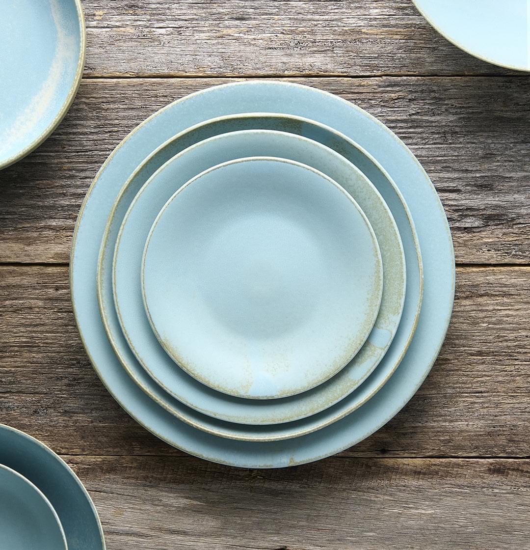 Stack of soda-blue glazed tapas plates with matching rims