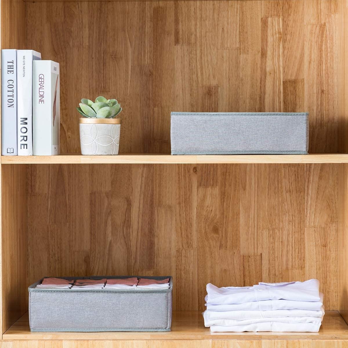 Gray fabric storage organizers on a shelf, holding folded clothes and blankets